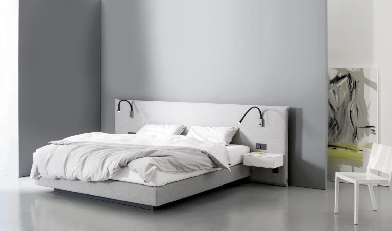 Flaches Boxspringbett mit gepolsterten Wandpaneel in flacher Kissenoptik